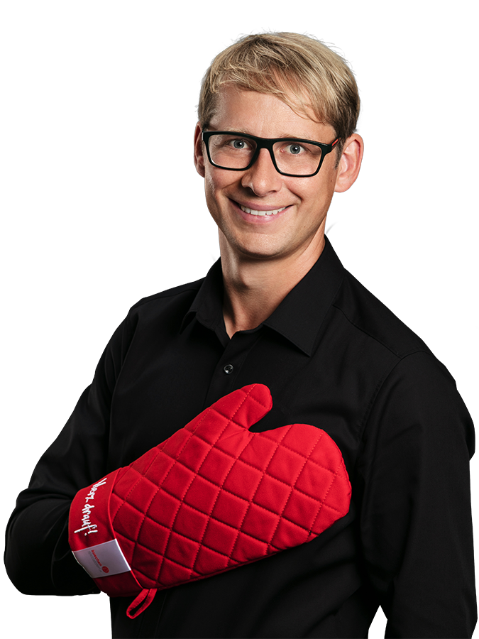 Georg Hartbauer im schwarzen Hemd mit rotem Ofenhandschuh